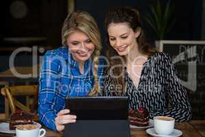 Smiling women using digital tablet in coffee shop