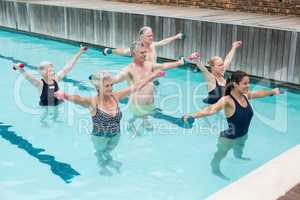 Trainer with senior people exercising in swimming pool