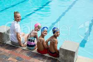 Cheerful swimming instructor and students at pool side
