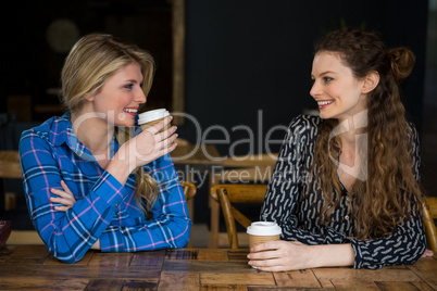 Smiling female friends having coffee while talking in cafe