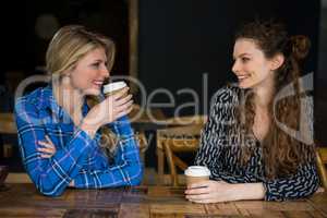 Smiling female friends having coffee while talking in cafe