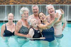 Female trainer taking selfie with senior swimmers in pool