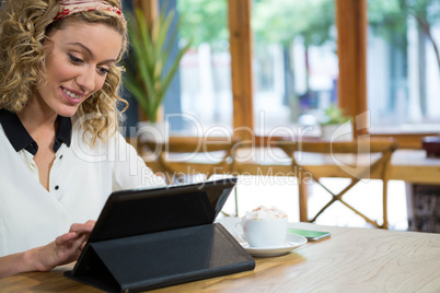 Beautiful woman using digital tablet at table in cafe