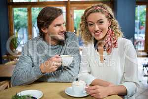 Happy young woman with man at table in coffee shop