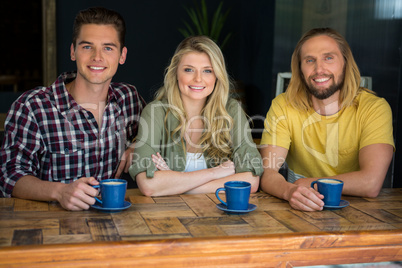 Happy friends having coffee at wooden table in cafe