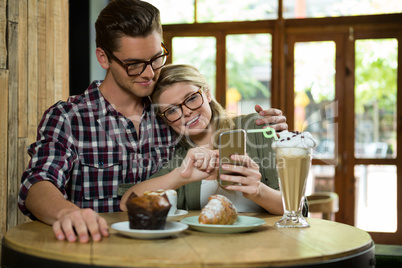 Loving couple using smart phone at table in coffee shop
