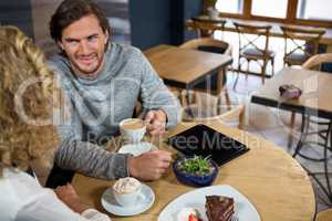 Man having coffee while talking with woman in cafe