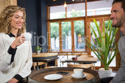 Couple talking while having coffee at table in cafe