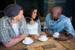 Friends talking while having coffee at table in coffee shop