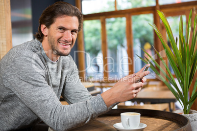 Smiling man talking on smart phone in coffee shop