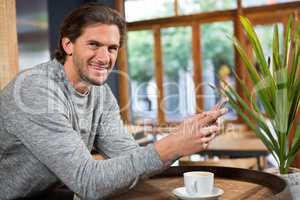 Smiling man talking on smart phone in coffee shop