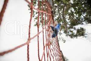 Woman climbing a net during obstacle course