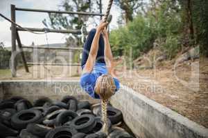 Woman climbing rope during obstacle course training