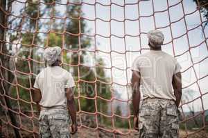 Military soldiers looking at net during obstacle course