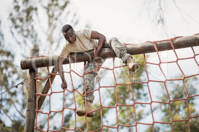 Military soldier climbing net during obstacle course