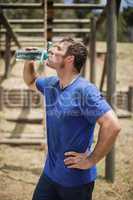 Man drinking water from bottle during obstacle course