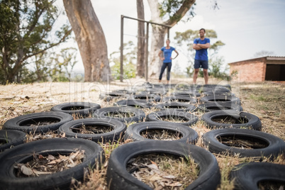 Man and woman standing near tyre during obstacle course