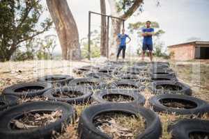 Man and woman standing near tyre during obstacle course