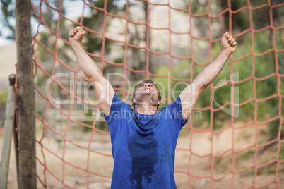 Happy man raising his hands during obstacle course