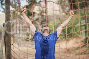 Happy man raising his hands during obstacle course