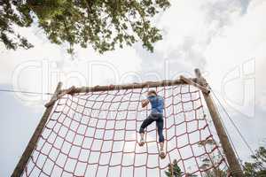 Fit woman climbing down the net during obstacle course