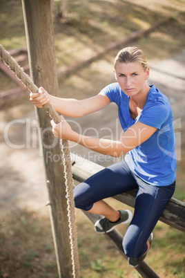 Determined fit woman climbing down the rope during obstacle course
