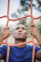 Fit man climbing a net during obstacle course