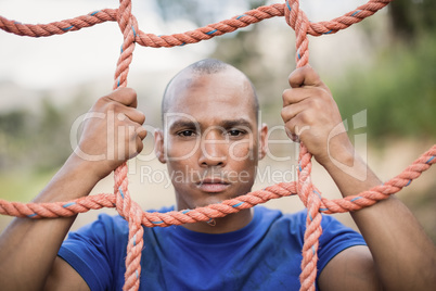 Portrait of fit man climbing a net during obstacle course