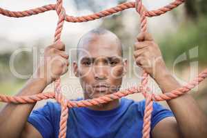 Portrait of fit man climbing a net during obstacle course