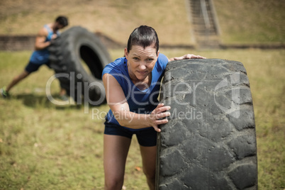 Fit woman flipping a tire during obstacle course