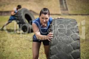 Fit woman flipping a tire during obstacle course