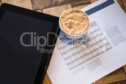Digital tablet with coffee and document on table