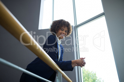 Businesswoman leaning over the railing of staircase