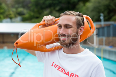 Male lifeguard carrying rescue can at poolside