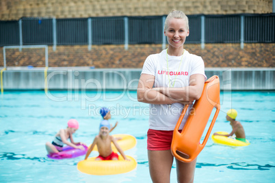 Female lifeguard standing with rescue can at poolside