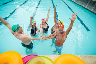 Active seniors stacking hands in pool