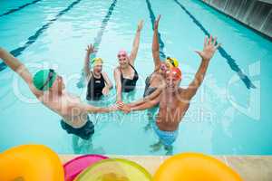 Active seniors stacking hands in pool