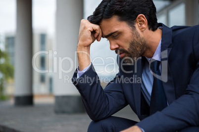 Depressed businessman sitting with hand on forehead