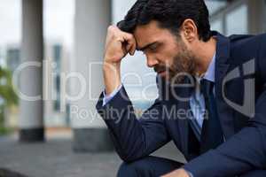 Depressed businessman sitting with hand on forehead