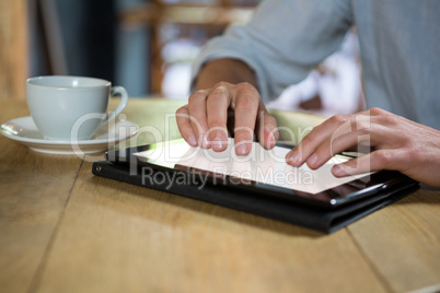 Man using digital tablet at table in coffee shop