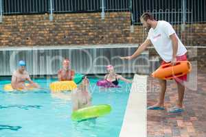 Lifeguard helping swimmers at poolside
