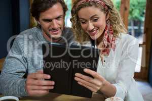Young couple using tablet computer at table in cafeteria