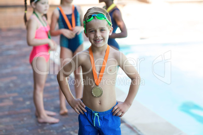 Happy little boy wearing medal at poolside