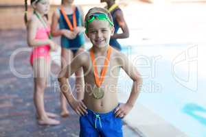 Happy little boy wearing medal at poolside