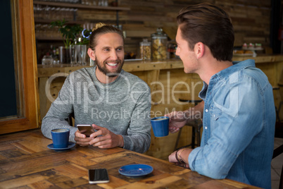 Smiling man talking with friend at table in coffee shop