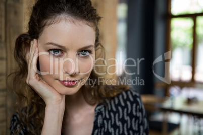Portrait of beautiful woman with hand on chin in cafe