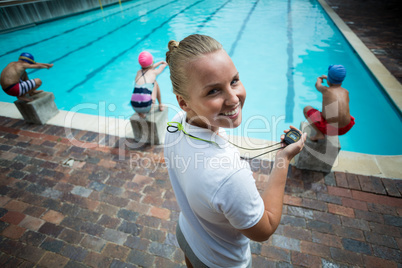 Cheerful Instructor monitoring children at poolside