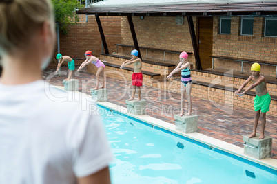 Female trainer looking at children at poolside