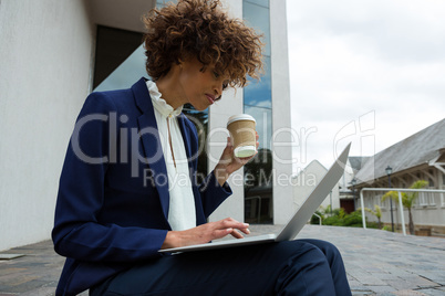 Businesswoman using laptop while having coffee