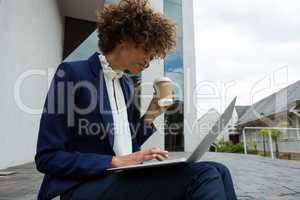 Businesswoman using laptop while having coffee
